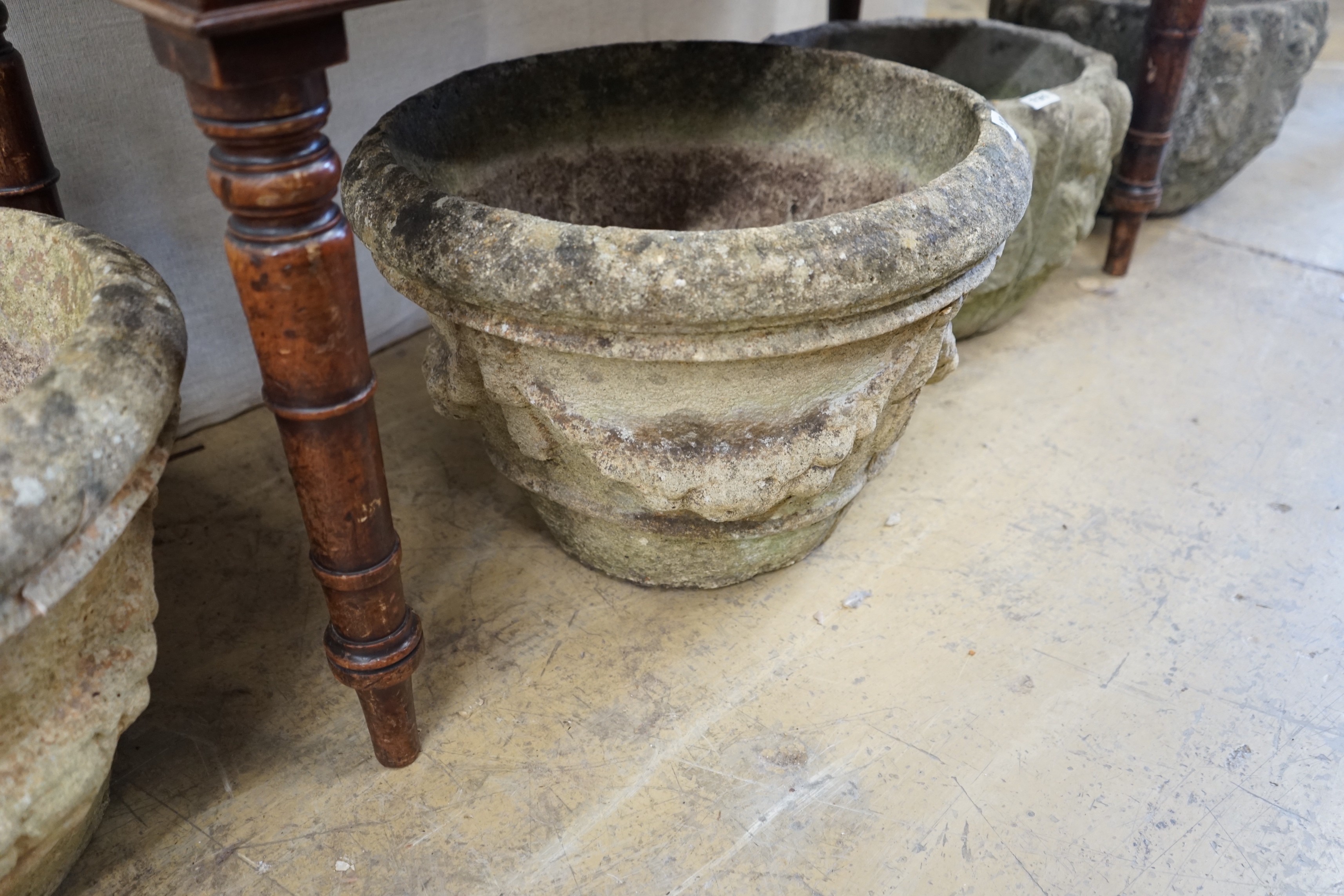 A pair of circular reconstituted stone garden urns with swagged floral bodies diameter 46cm height 33cm